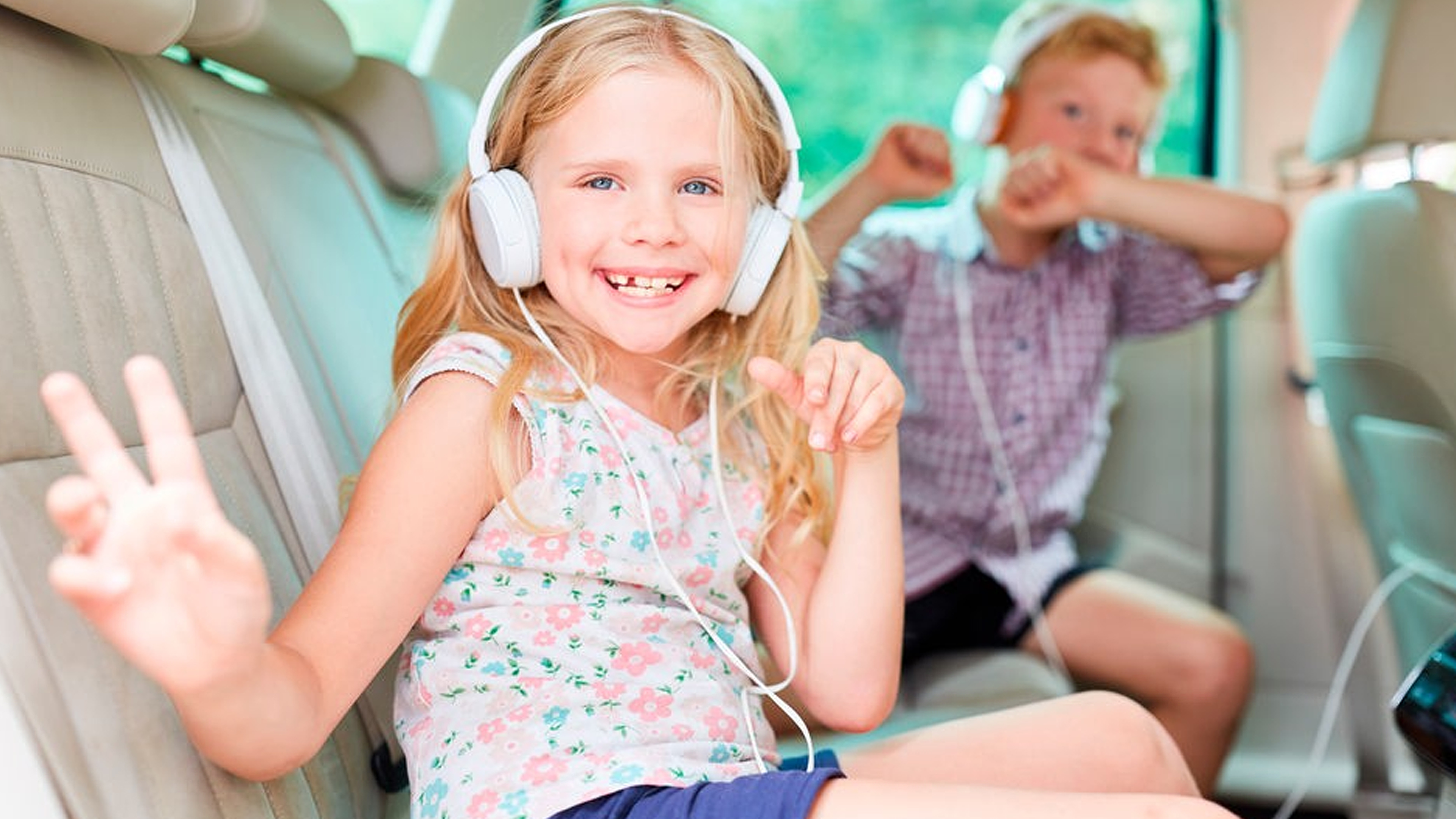 Junge und Mädchen mit Kopfhörern auf der Rückbank im Auto