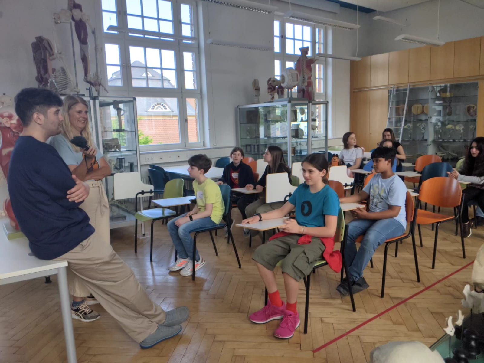Eine Gruppe von Schülerinnen und Schülern sitzt in einem alten Klassenraum zusammen.