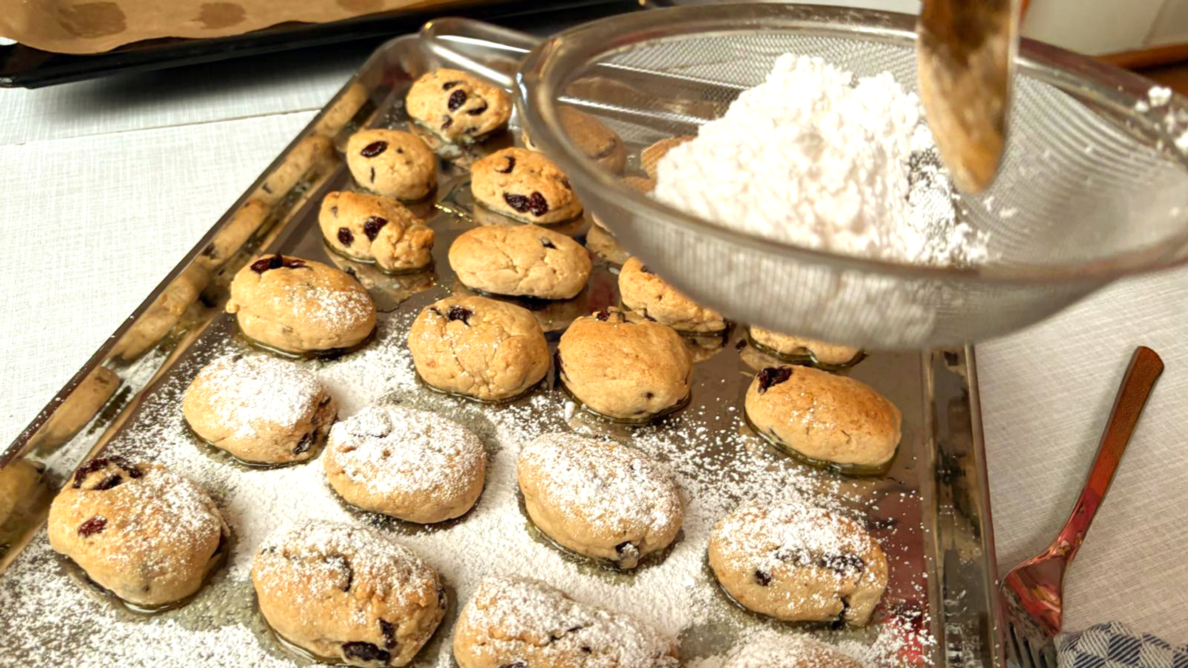 Frisch gebackene Ministollen werden mit Puderzucker überstreut