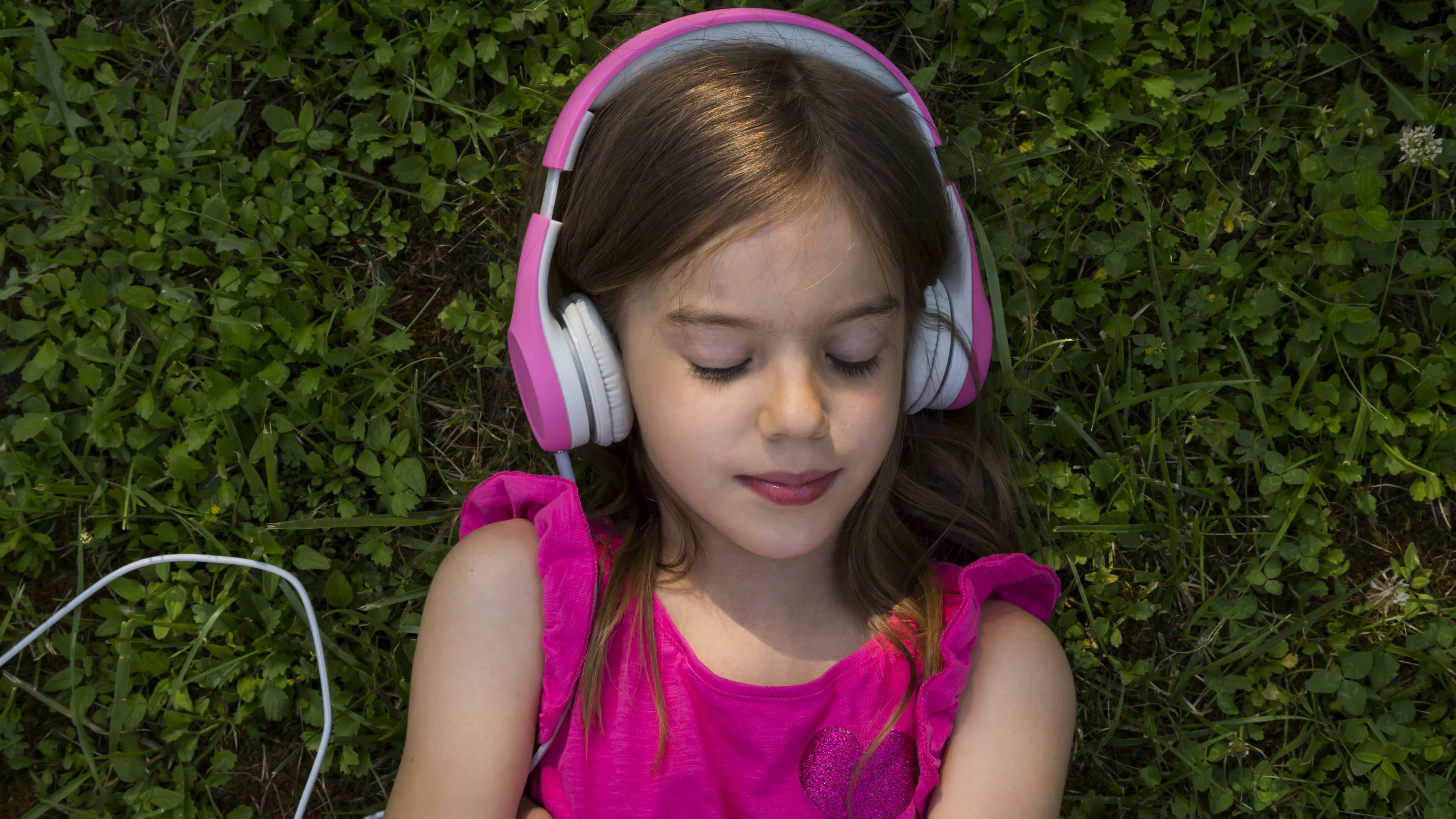 Mädchen liegt auf Gras und hört Musik