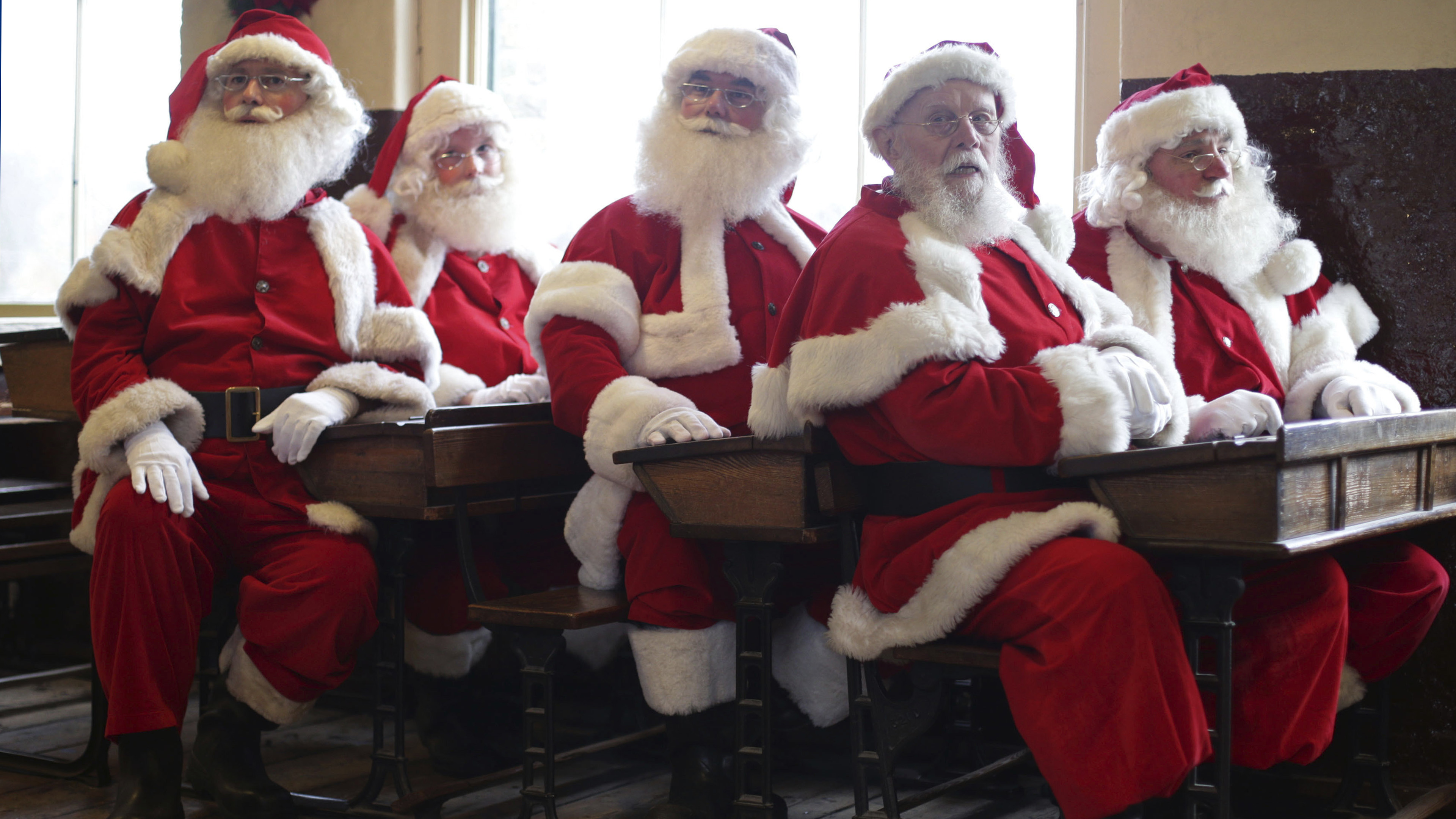 Weihnachtsmänner sitzen auf Schulbänken