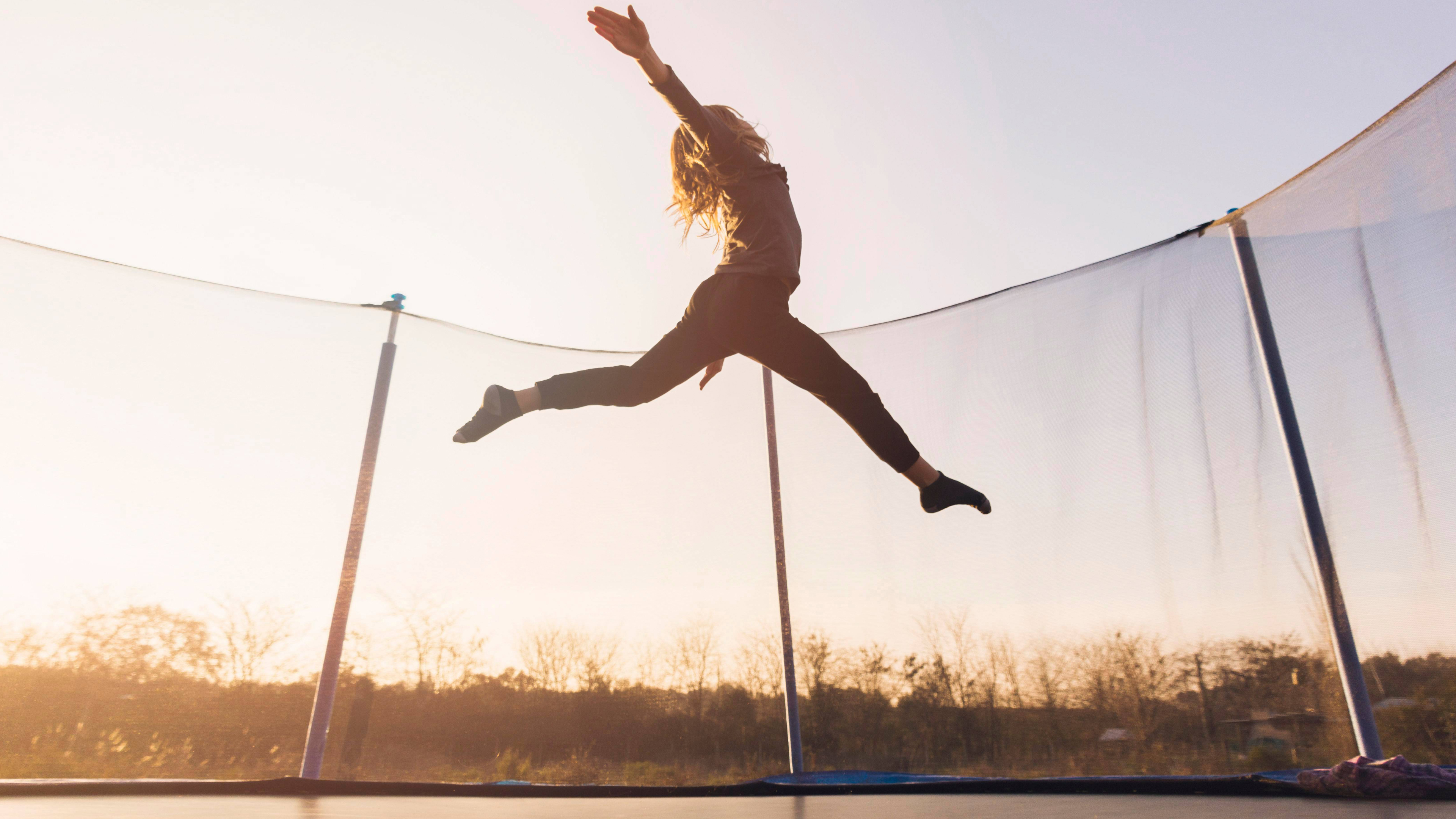 Mädchen springt Trampolin gegen den Himmel