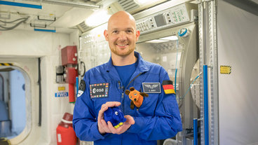 Astronaut Alexander Gerst mit Elefant und Maus als Plüschtiere