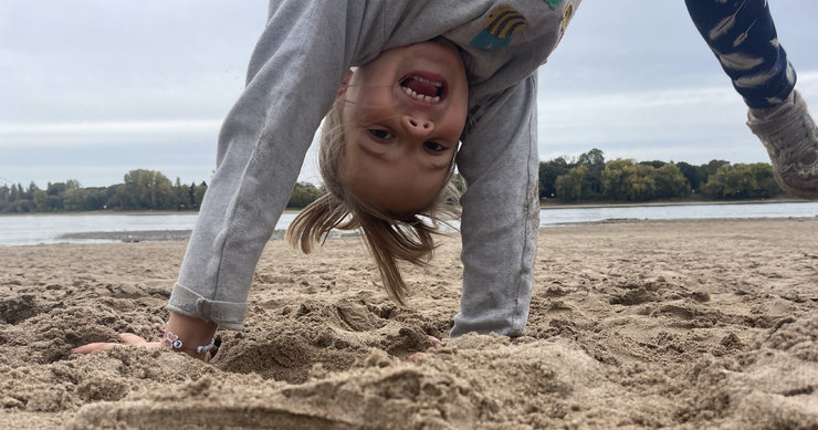 lachendes Kind schlägt ein Rad in Nahaufnahme auf Sand