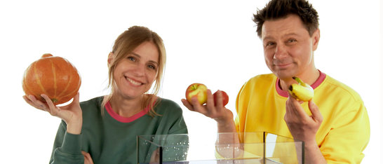 André Gatzke und Tanja Mairhofer halten Gemüse und Obst für ihr Experiment hoch.