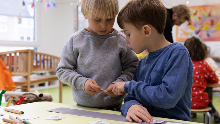 Zwei Kinder am Tisch spielen mit Arbeitsblättern von Programmieren mit dem Elefanten