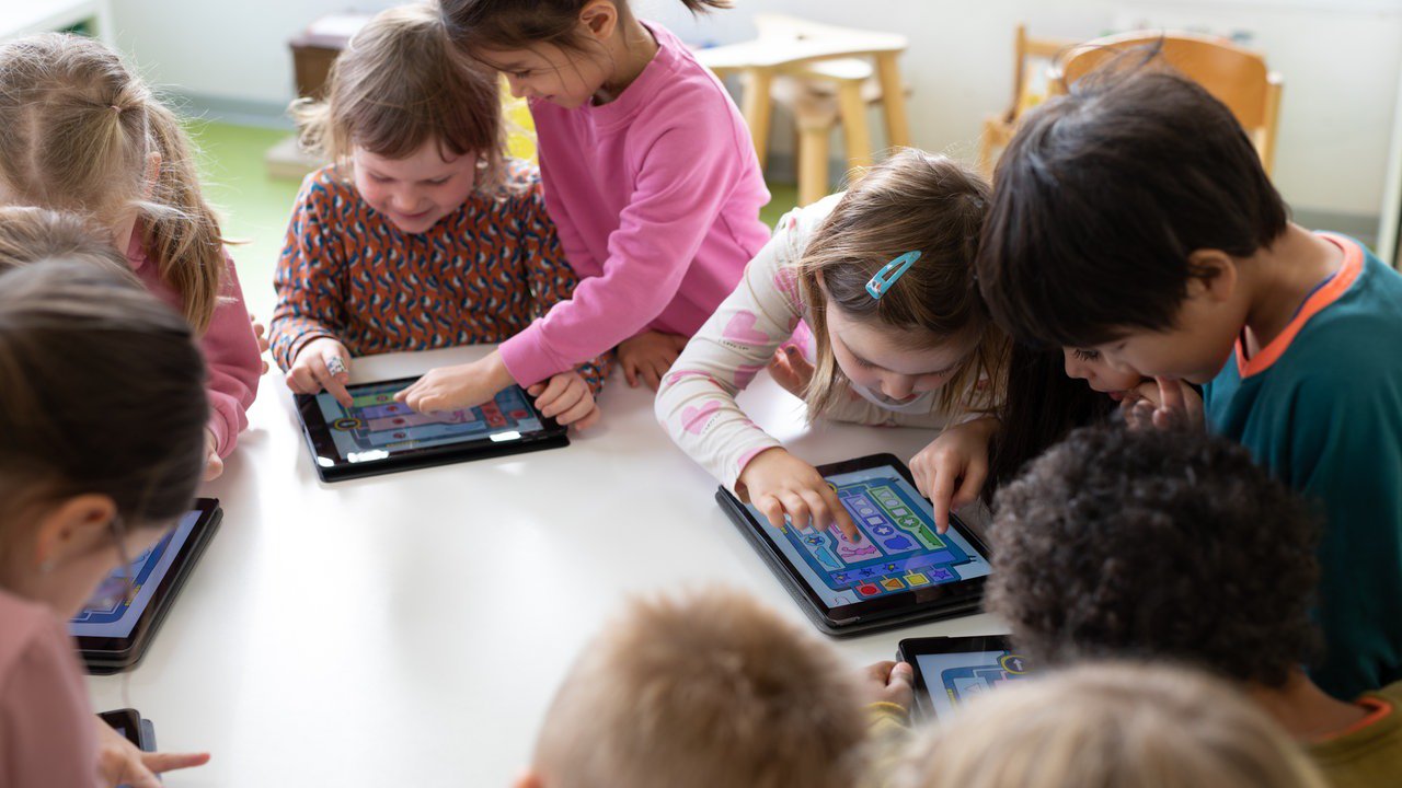 Kinder spielen in Zweiergruppen die Wenn-Dann-Maschine auf Tablets