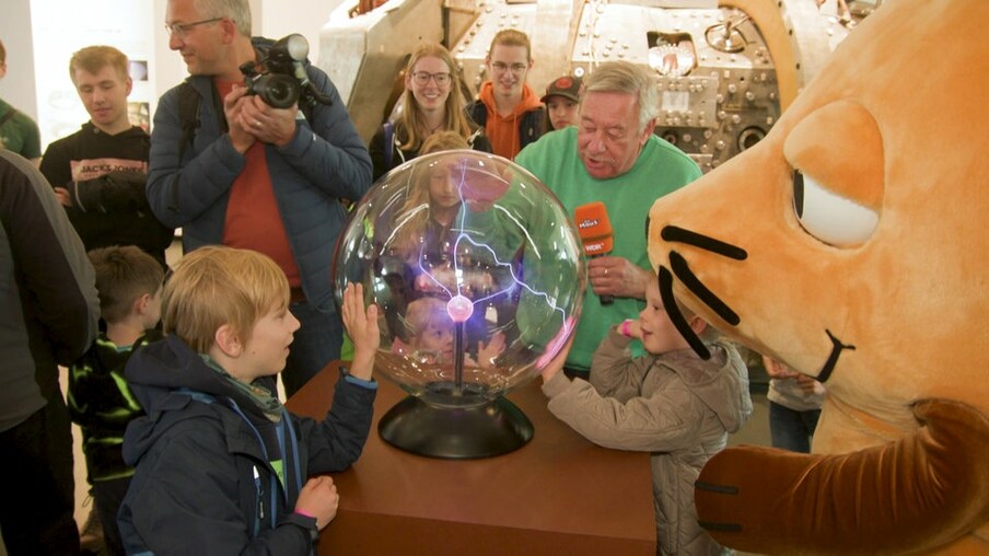 Christoph und die Maus stehen mit Kindern um eine experimentelle Kugel herum